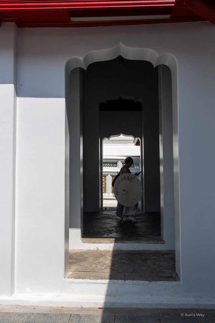 Silhouette avec ombrelle asiatique dans l'encadrement d'une porte au temple Wat Arun