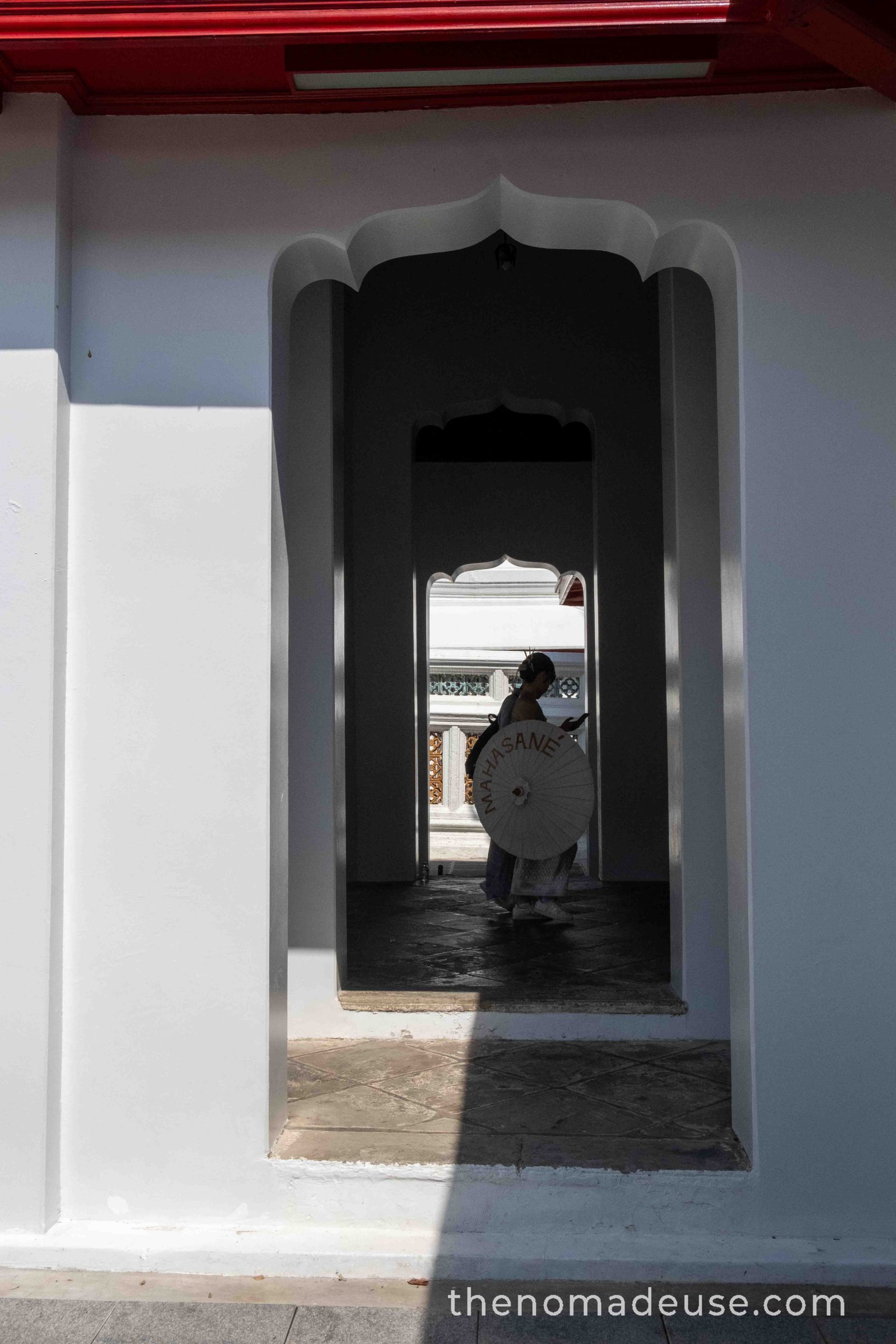 Silhouette avec ombrelle asiatique dans l'encadrement d'une porte au temple Wat Arun