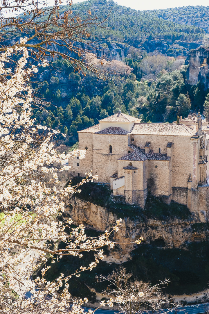 Vue sur le Parador de Cuenca avec un amandier en fleur au premier plan.