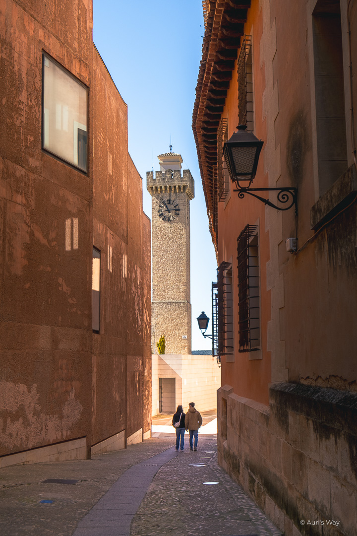 Couple avançant dans une rue étroite débouchant sur la tour de Mangana à Cuenca.