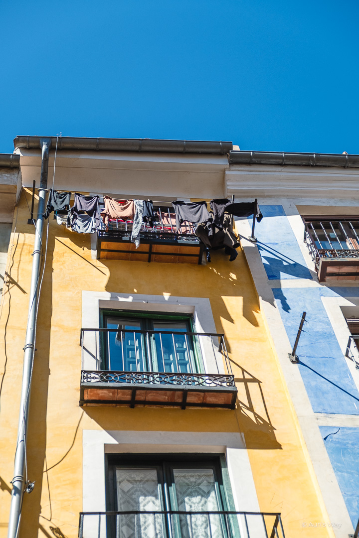 Façade jaune vif des rascacielos de Cuenca, avec linge séchant sur une ligne.