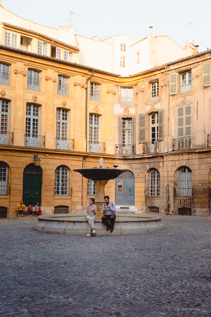 Couple en train de manger une glace assis sur la fontaine de la place d'Albertas, un incontournable à Aix-en-Provence.
