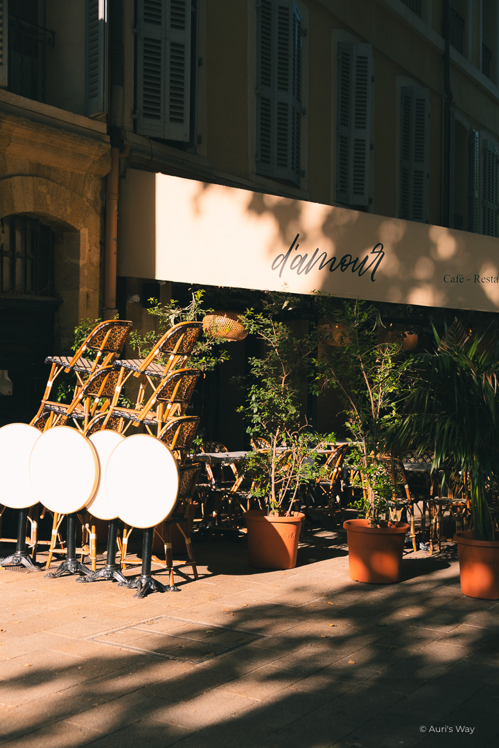 Un café sur le Cours Mirabeau d'Aix en Provence illuminé par le soleil du matin, montrant le mot "d'amour".