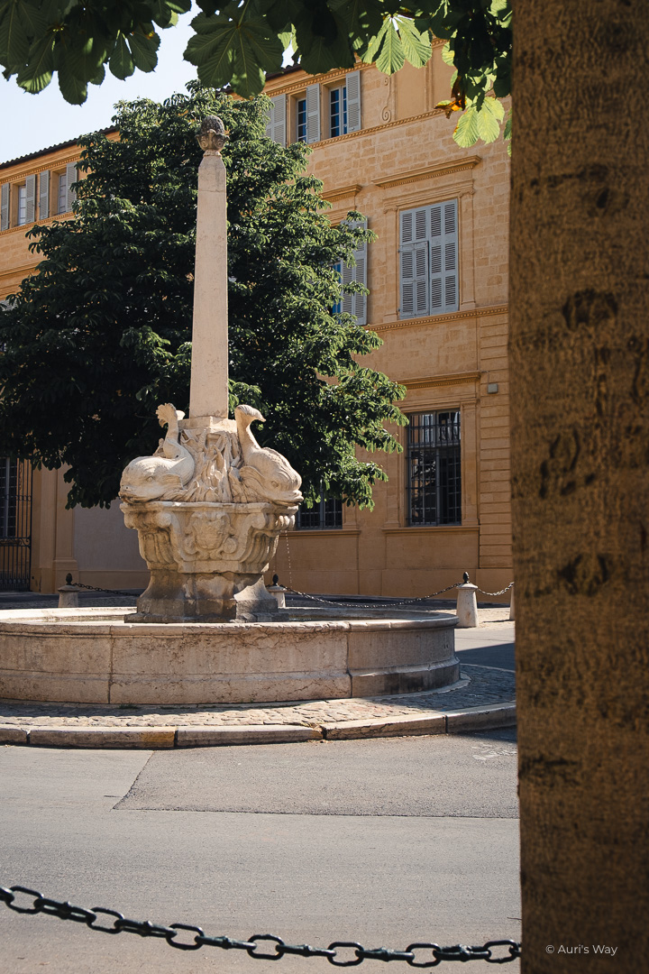 Fontaine des Quatre Dauphins à Aix avec un arbre au premier plan.