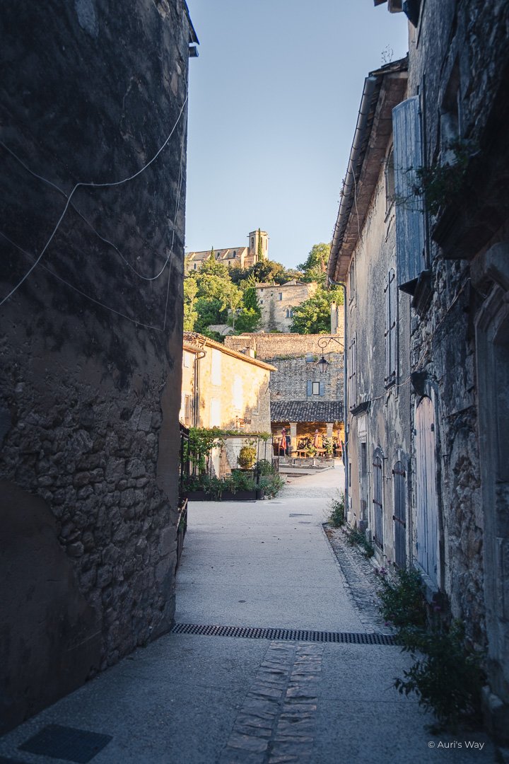Ruelle en pierre débouchant sur la place d'un village provençal.